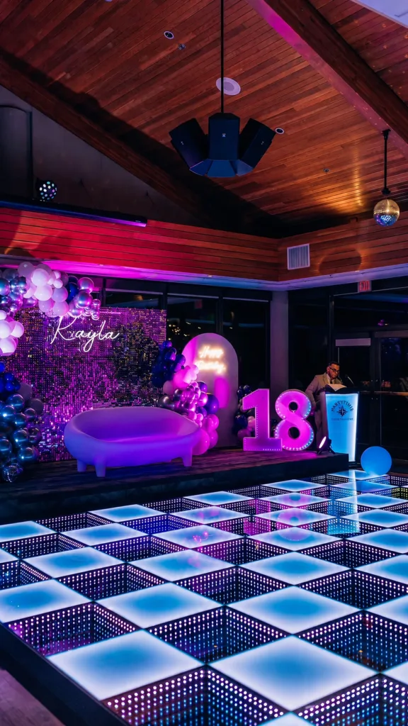 Wit-blauw verlichte LED-dansvloer op een verjaardagsfeest, met ballonnenboog en lichtletters met het cijfer 18