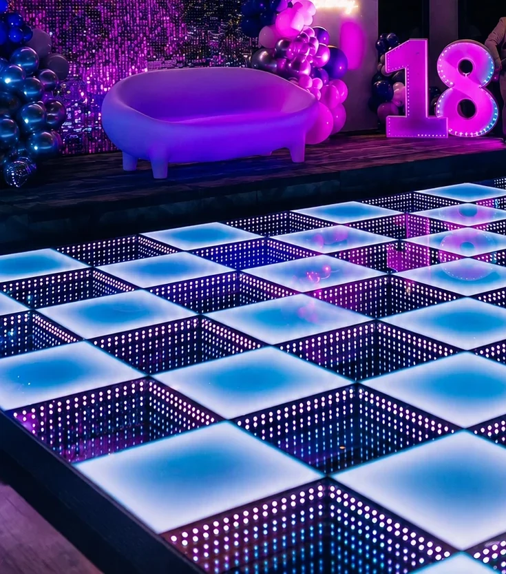 Verlichte LED-dansvloer in een feestzaal, met een verlicht 18-bord en een ballonnenboog op de achtergrond
